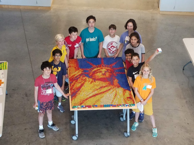 Children standing around Rubik's cube mosaic of the Statue of Liberty